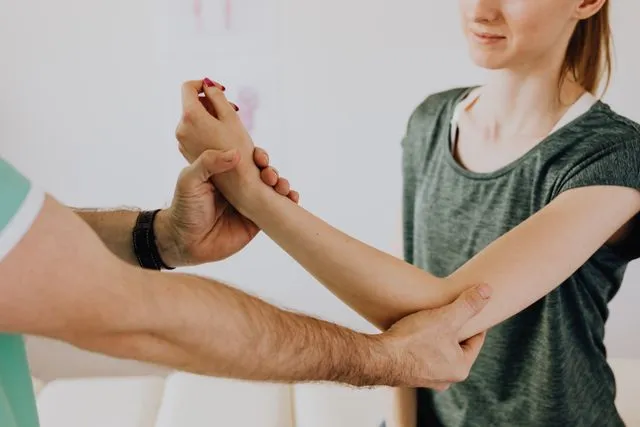 Profissional de Fisioterapia realizando atividade com braço de paciente